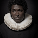 A portrait of a person in a black coat and a white collar